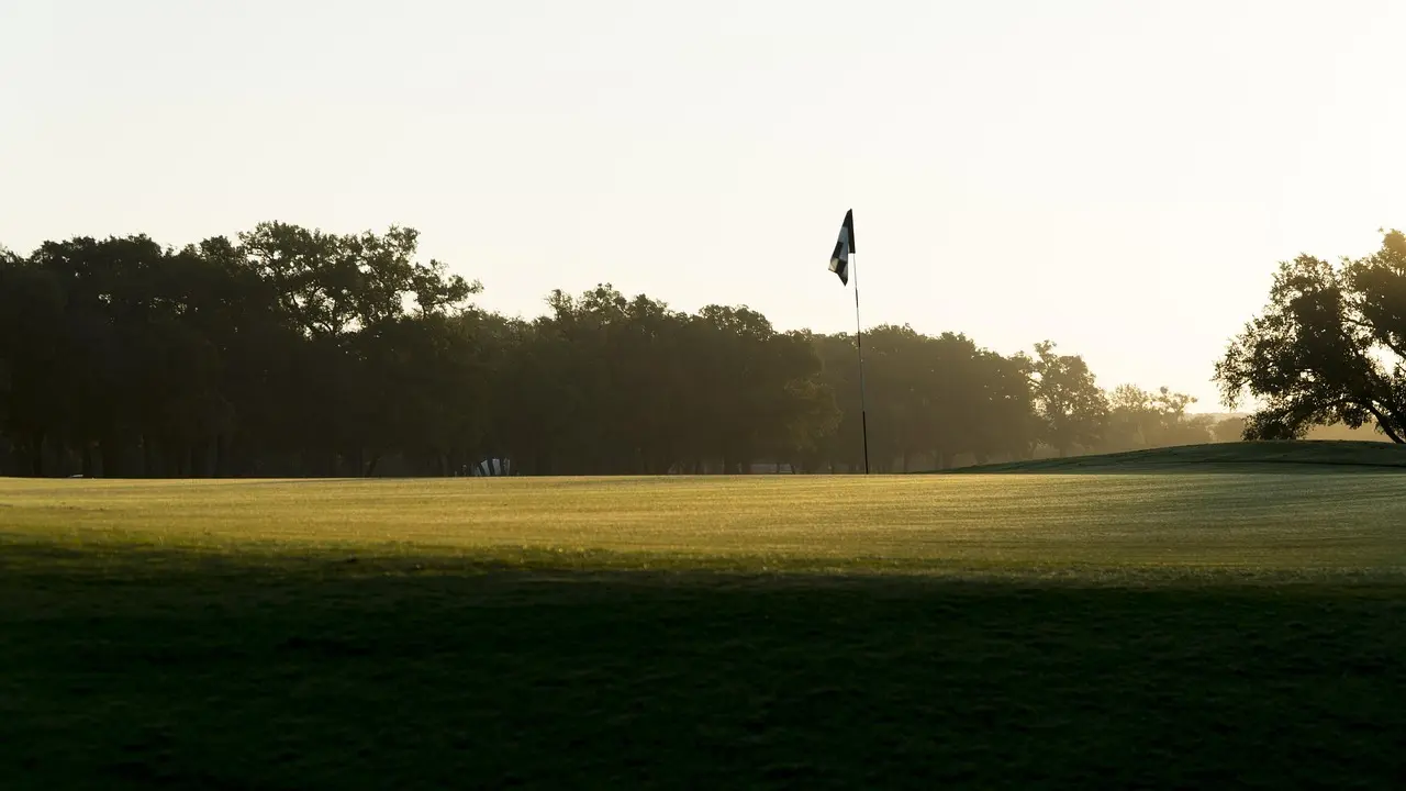 Golfgreen med flag i solopgang